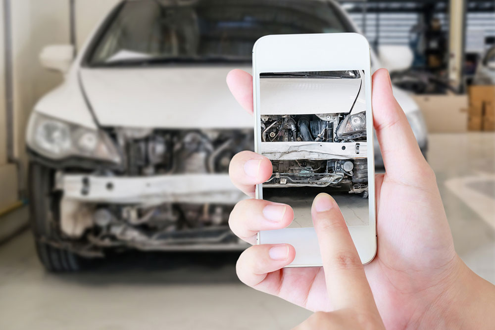 Mujer tomando fotos de un accidente de auto con su teléfono para documentar el reclamo de seguro